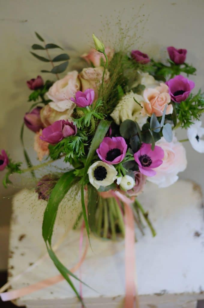 an image of a spring wedding bridal bouquet of anemones in pink and white on a white vintage stool