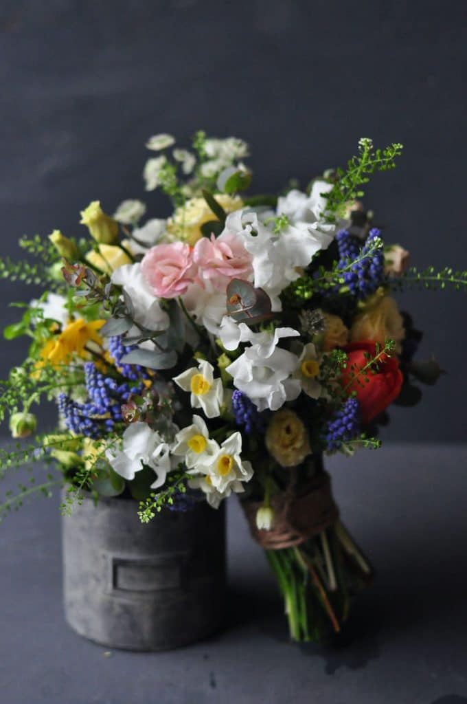 an image of a bridal bouquet for a March wedding using delicate flowers against a grey backdrop