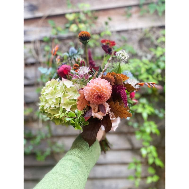 A relaxed boho bridal bouquet which is showing seasonal flowers including dahlias, seed pod heads and hydrangeas