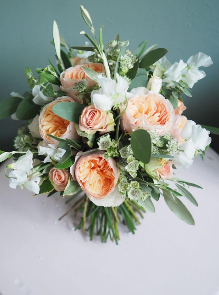 a hand-tied bridal bouquet of peach Juliette David Austin roses, sweet peas an