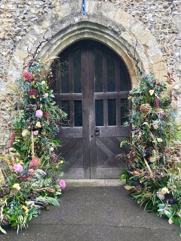 wedding flower archway at a traditional church wedding. The image shows a deconstructed wedding flower arch with autumn flowers 