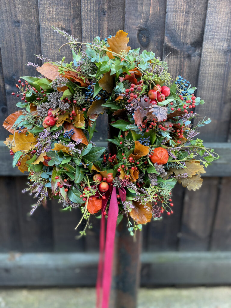 Textured autumn wreath with layers of seasonal flowers, berries, and leaves