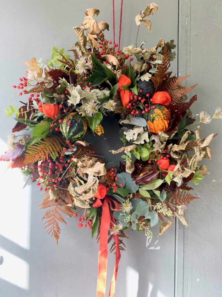 Rustic autumn door wreath with moss, berries, and seasonal foliage