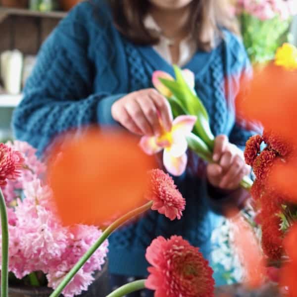 Hands on flower arranging class for beginners with people working with flowers and scissors