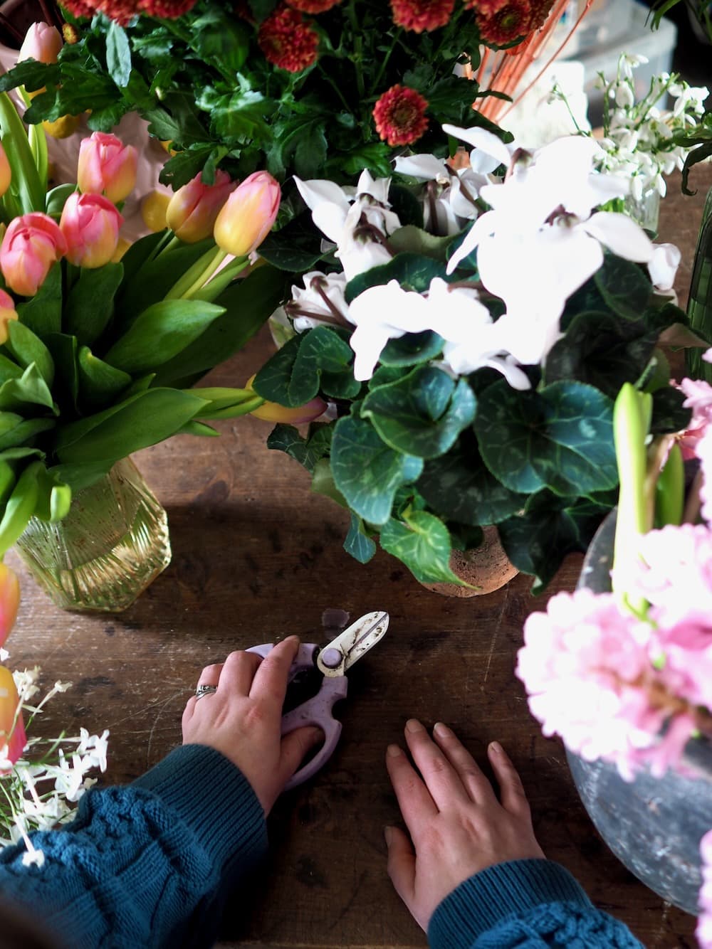 Close up of hands holding seasonal flowers during a beginner floristry workshop